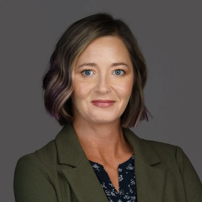 Jessica Mychal Moore, smiling, wearing an olive green blazer
